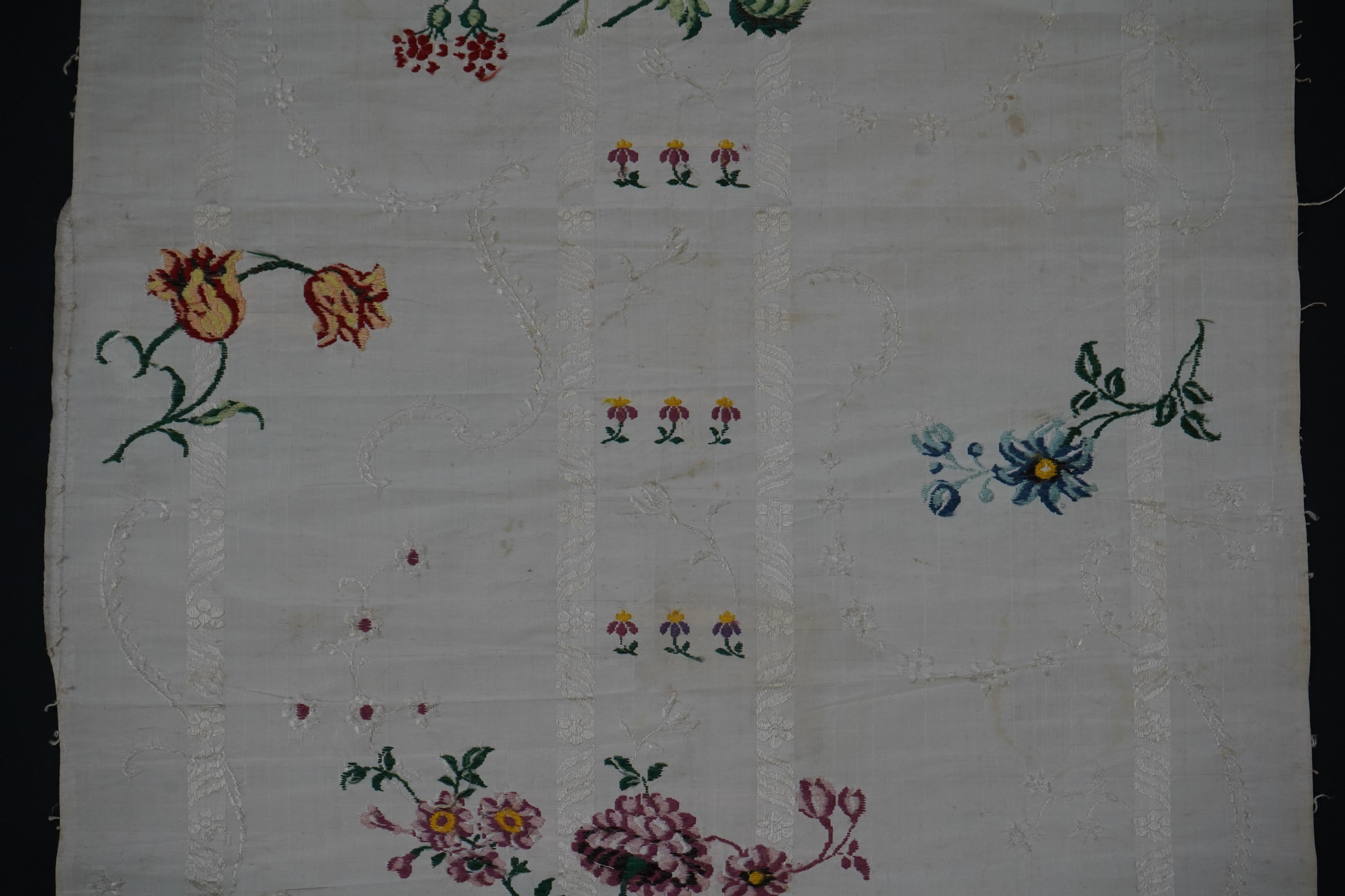 A length of 18th century short loom hand woven Spitalfields silk dress fabric, woven in cream silk with all over multicoloured spot floral motifs in a large repeat. 82cm repeat, total length of fabric 100cm x 48.5cm wide